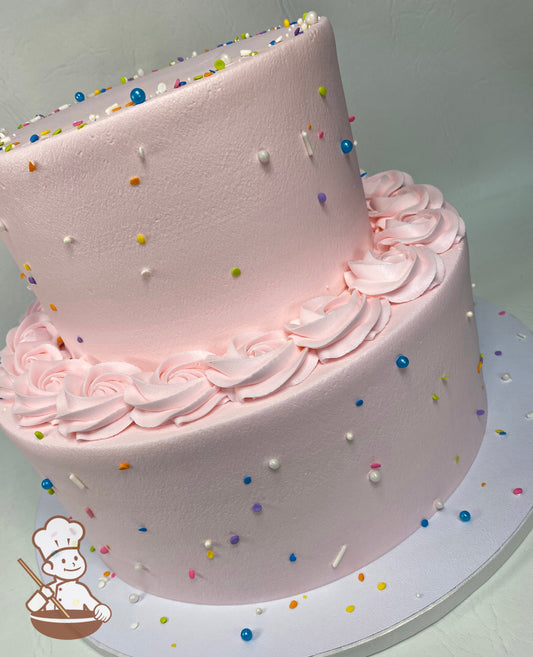 2-tier round cake with light pink icing and colorful sprinkles all over cake walls and light pink buttercream rosette trim on top of bottom tier.