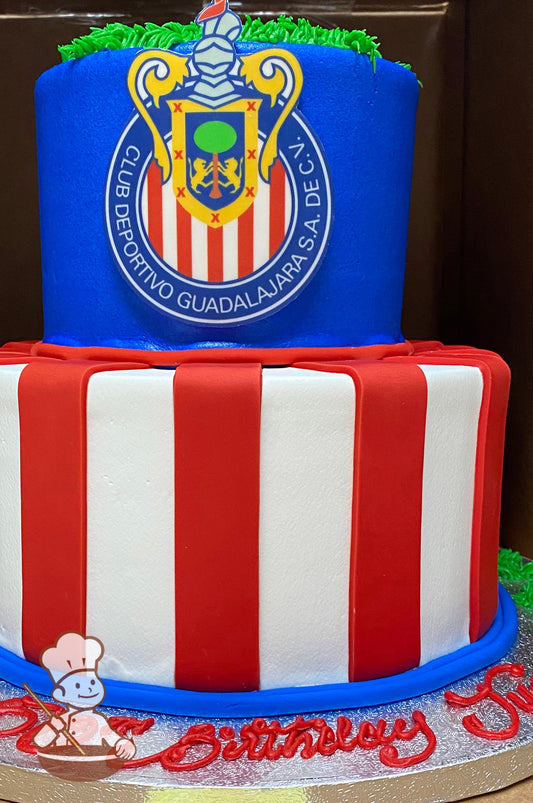 2-tier cake with white icing and red fondant stripes on the bottom tier. The top tier has blue icing and the Chivas logo in the front center.