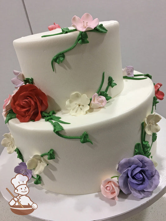 2-tier cake with smooth white icing and decorated with sugar roses and sugar blossoms in a variety of colors.