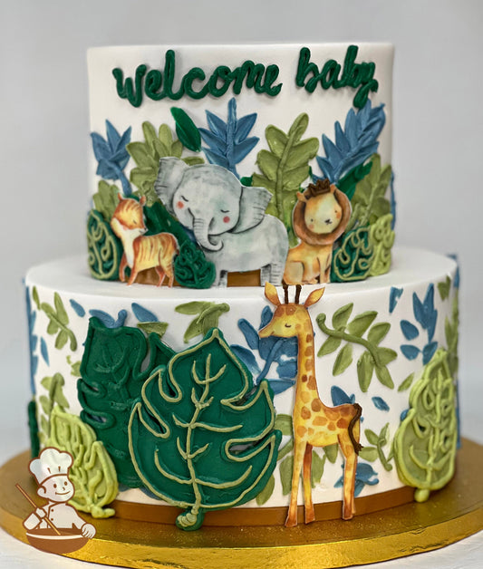 Cake with white icing and decorated with printed images of safari animals and buttercream leaves in a variety of green and dusty blue colors.