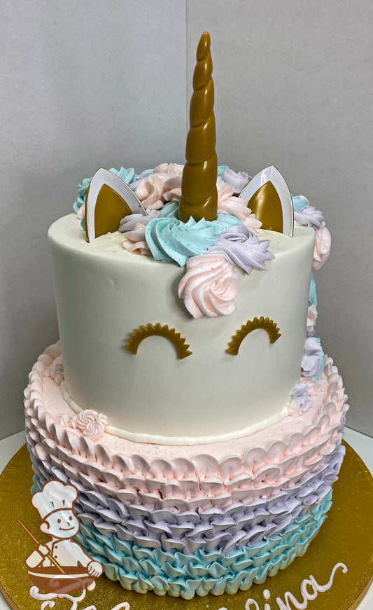 Cake with light-blue, light-pink and lavender icing decorated with a buttercream ruffle texture and a plastic horn, ears and eyes.