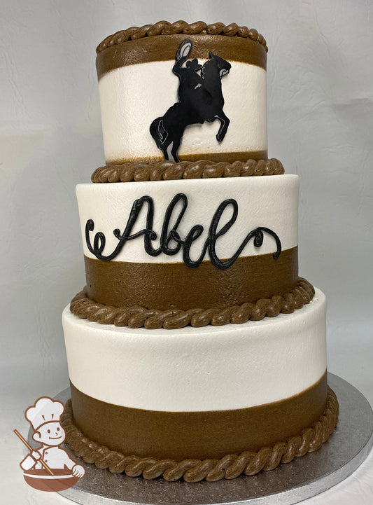 3-tier cake with white and brown icing, decorated with buttercream rope trims and a cowboy on a horse on the cake wall of the top tier.
