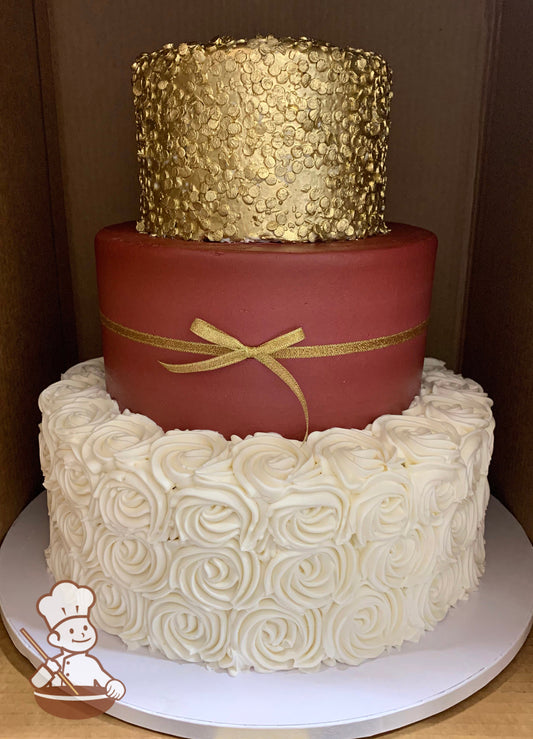Cake with white buttercream rosettes on the bottom tier, burgundy icing and a gold ribbon on the middle tier and gold sprinkles on the top tier.