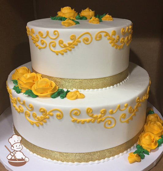 2-tier round cake with white icing and decorated with a gold ribbon, yellow-gold buttercream scrolls and yellow-gold roses with green leaves.
