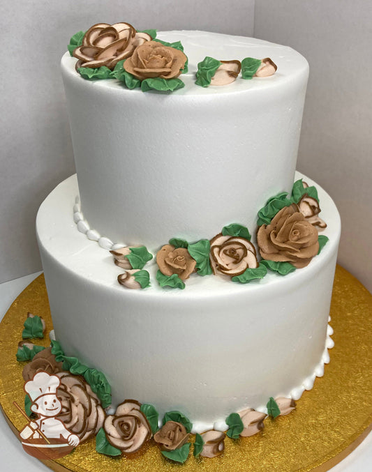 2-tier round cake with buttercream roses in brown and light brown with brown edges and green leaves.