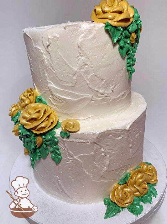 2-tier round cake with textured ivory icing and yellow-gold buttercream roses and green leaves.