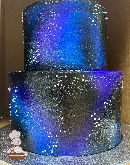 2-tier round cake with white icing and added airbrushed coloring to look like a galaxy in black, blues and white colors.