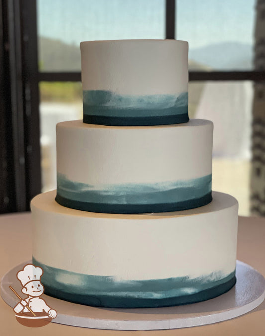 3-tier round cake with smooth white icing and added blue colored buttercream started at the base of each tier then smeared to white on top.