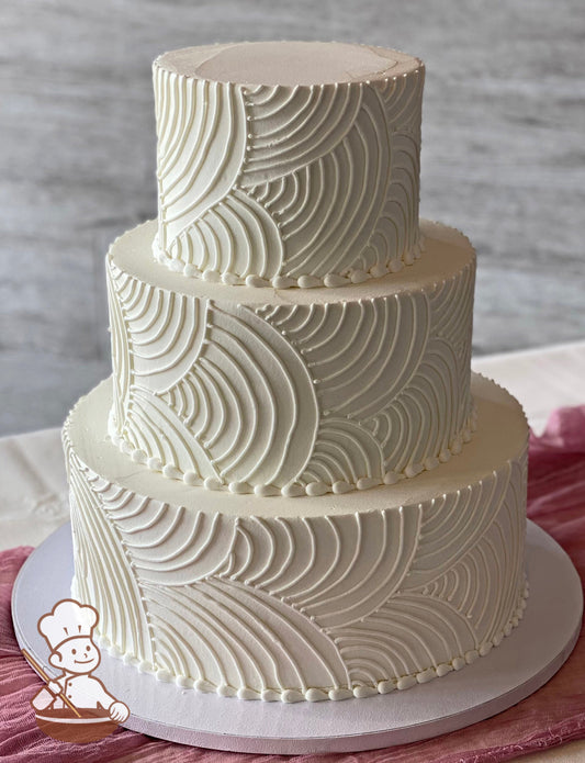 3-tier round cake with smooth white icing and hand-piped white buttercream curved lines all over cake walls. The cake has white beaded trims.