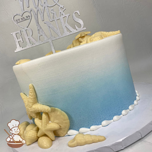 Single tier round cake with a blue Ombre coloring and ivory-color edible seashells.