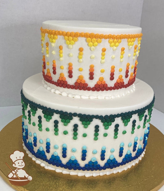 2-tier cake with white icing, decorated with multi color buttercream dots in orange, yellow, red, green, and blue tones fading into an Ombre.