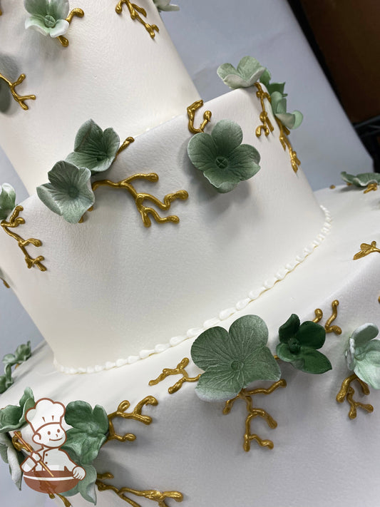 3-tier cake with smooth white icing and sugar blossoms which have been airbrushed a green color and metallic gold royal icing vines.