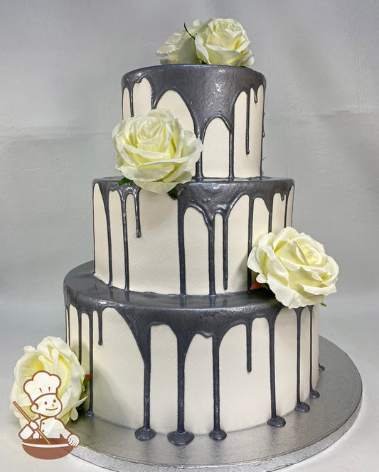 3-tier cake with smooth white icing, decorated with a silver drip and ivory silk roses.