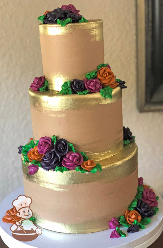 3-tier cake decorated with gold paint on the base and top of the tiers and clusters of buttercream roses in purple, magenta and orange colors.