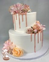 2-tier cake with smooth white icing and decorated with a pink drip and silk flowers in pastel pink shades.