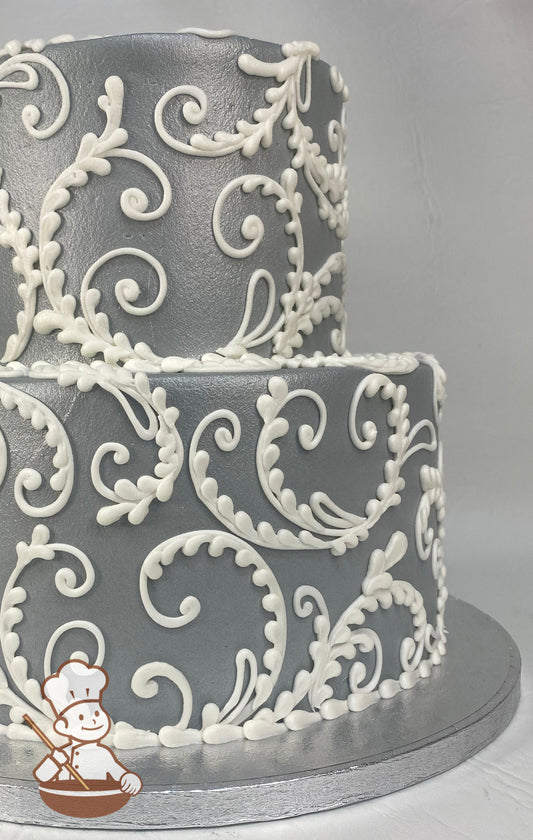 2-tier cake with grey smooth buttercream icing and hand-piped scrolls in white buttercream.