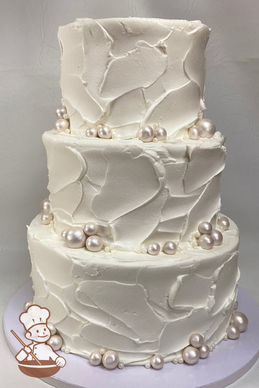 3 tier textured buttercream wedding cake with pearlescent fondant pearl decoration.