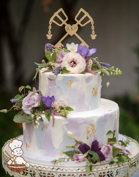2 tier round wedding cake with multi color textured buttercream and decorated with fresh flowers with gold lef accents.