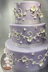 3 tier round periwinkle colored buttercream cake with white piping and decorated with white sugar flowers.