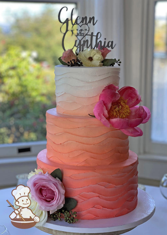 3-tier cake with white icing that has an added wavy texture and orange ombre coloring darkest at the bottom to white on top of the cake.