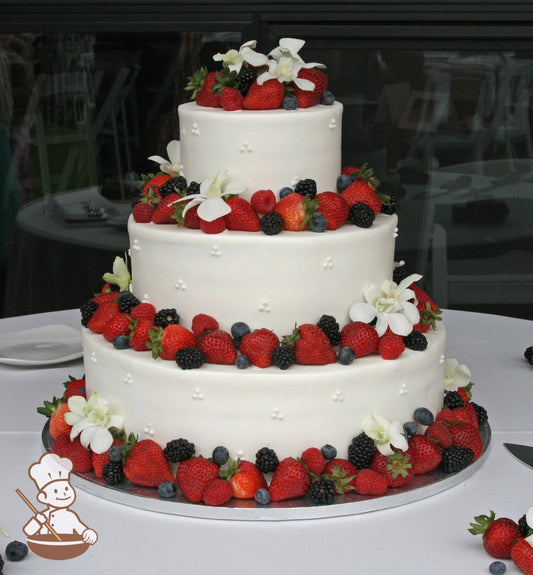 3-tier cake with smooth white icing and decorated with white buttercream tridots and fresh strawberries, blackberries and blueberries.