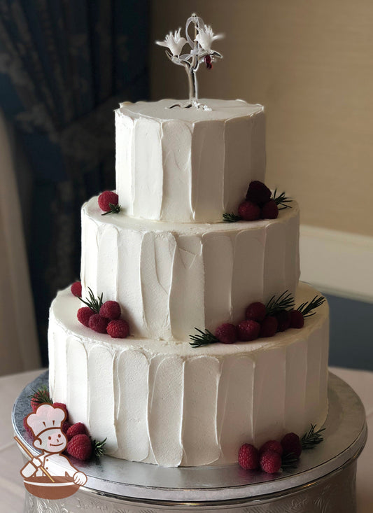 3-tier cake with white icing and decorated with a vertical texture and fresh raspberries.