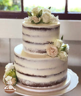 2-tier cake with white icing and decorated with a scraped texture to show some of the cake and fresh flowers.