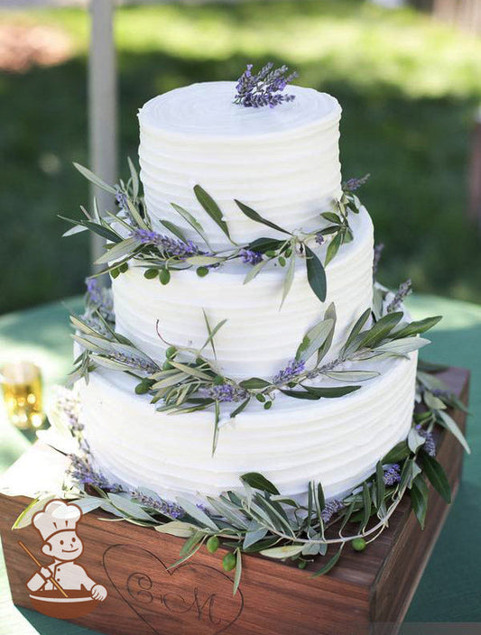 3-tier cake with white icing and decorated with a horizontal texture and lavender plants and vines.