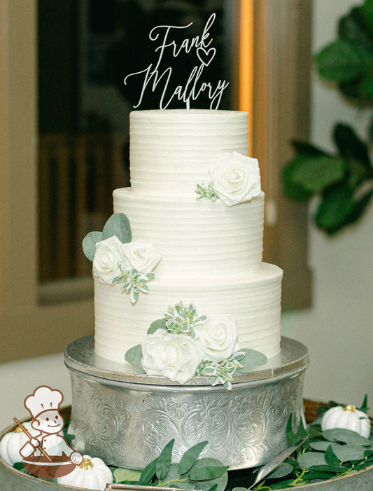 3-tier cake with white icing and decorated with a thin horizontal texture and white flowers.