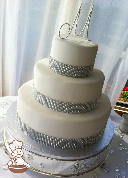 3 tier white fondant cover wedding cake decorated with tall rhinestone bands wrapped on base of each tier.