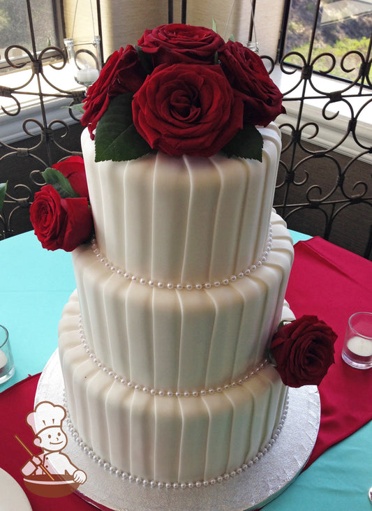 3 tier wedding cake with vertical overlapping fondant stripes and decorated with fresh red roses.