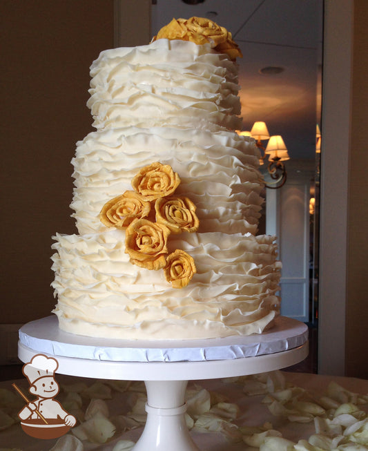 3 tier wedding cake covered with ivory fondant ruffles and decorated with gold wafer paper flowers.