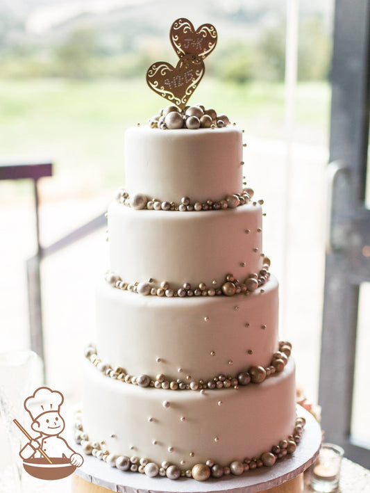 4 tier wedding cake with white fondant cover and decorated with metallic fondant pearls.
