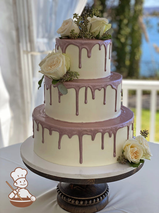3-tier cake with smooth white icing and decorated with a metallic rose-gold drip and white roses.