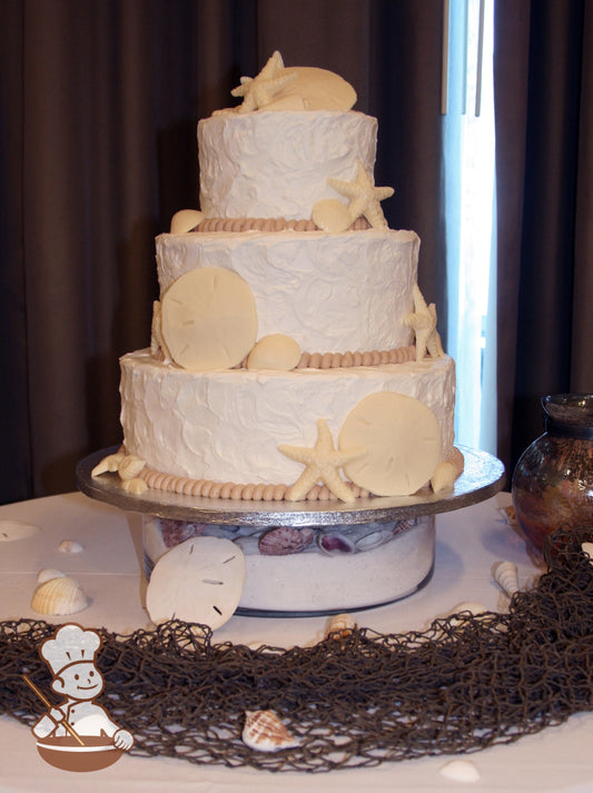 3-tier cake with stucco textured walls. Decorated with large sand dollars and star fish.