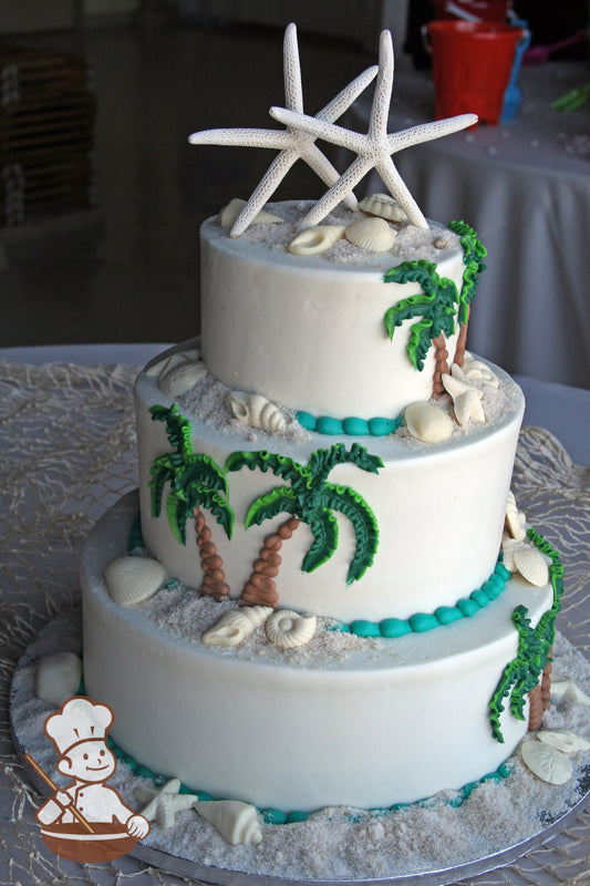 3-tier cake with white sugar sand and seashells. Hand drawn palm tress decorated on cake walls.