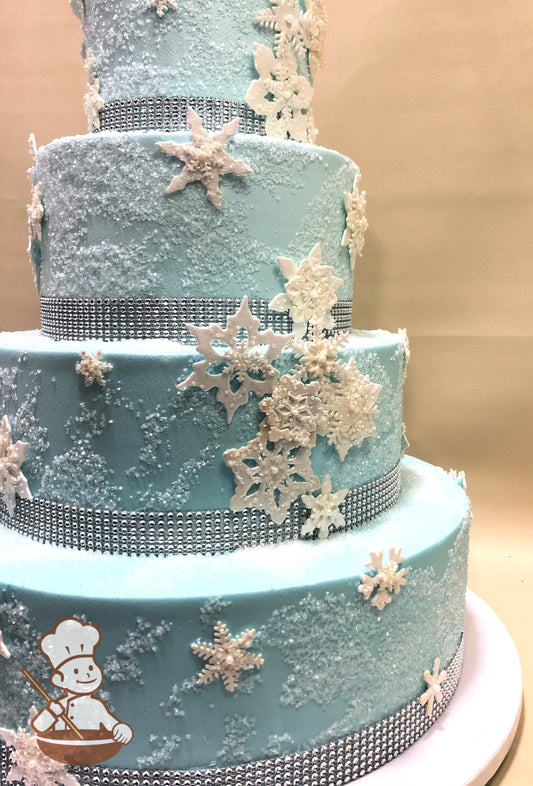 4-tier baby blue cake with sugar sparkles, rhinestone band and shimmering snowflakes.