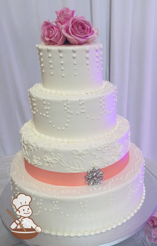 4-tier cake with smooth white icing and decorated with different white buttercream piping's and a peach-colored ribbon with a silver brooch.