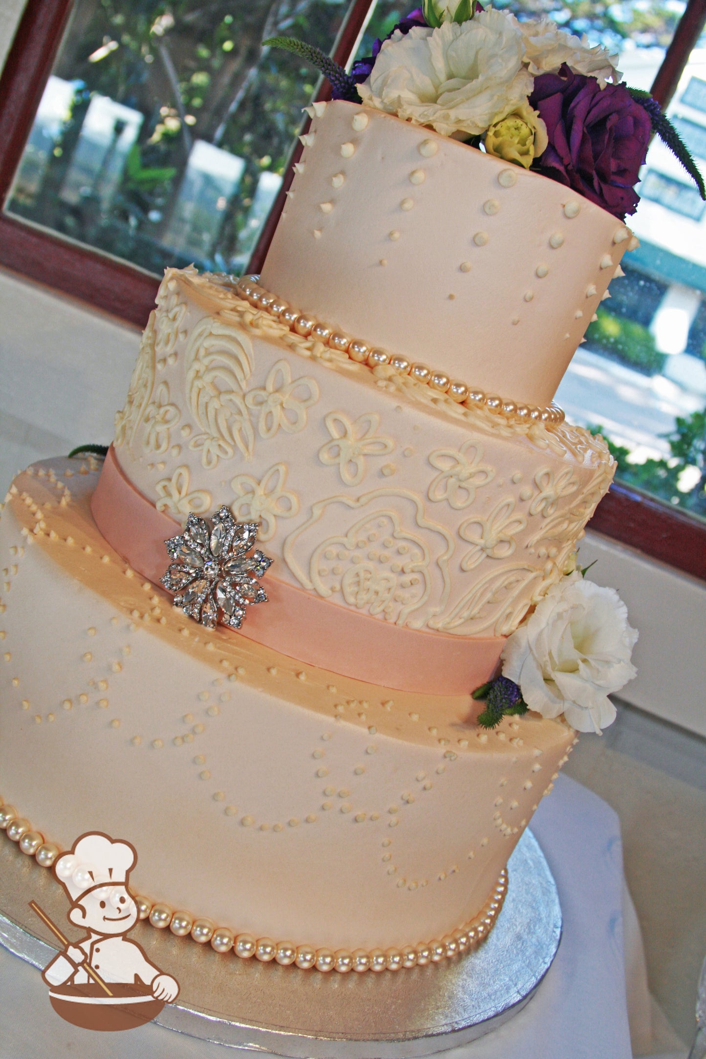 3-tier cake with smooth white icing and decorated with different white buttercream piping's and a light-pink fondant band and pearl beads.