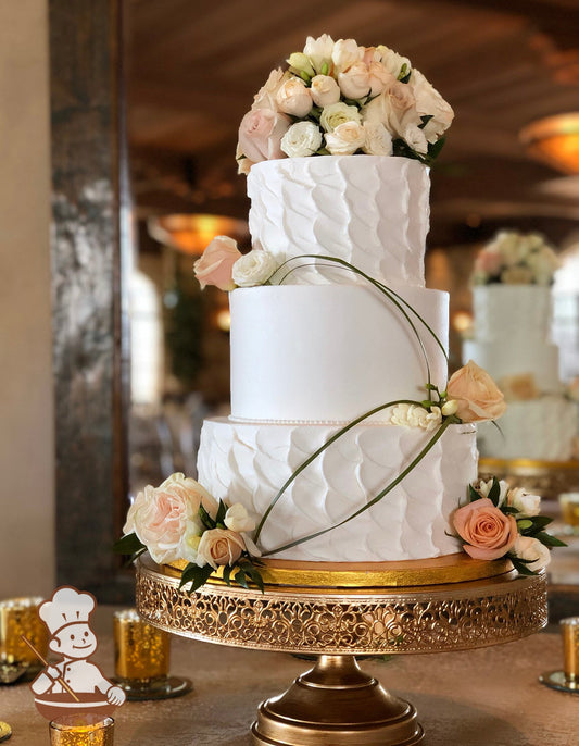 3 tier round cake with textured bottom and top tier and smooth middle tier. Fresh flowers with elongated grass strands added for an elegant look.