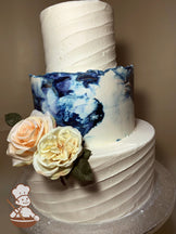 3 tier wedding cake with dark & light blues marble buttercream in middle and diagonal texture for bottom and top tiers.  Pastel flowers added.