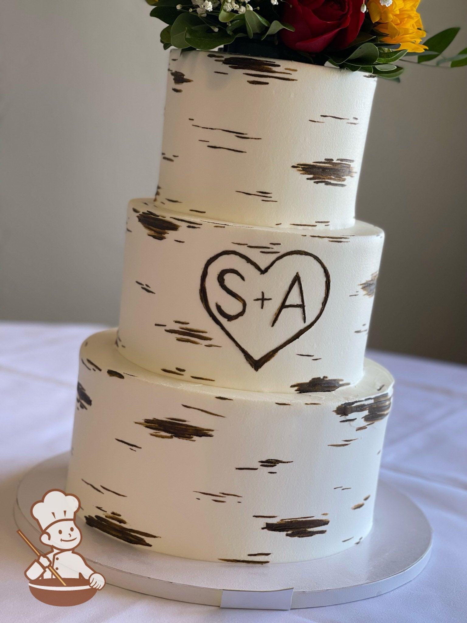 3-tier cake with smooth white icing and decorated with a painted wood grain look and a heart with the initials S + A.