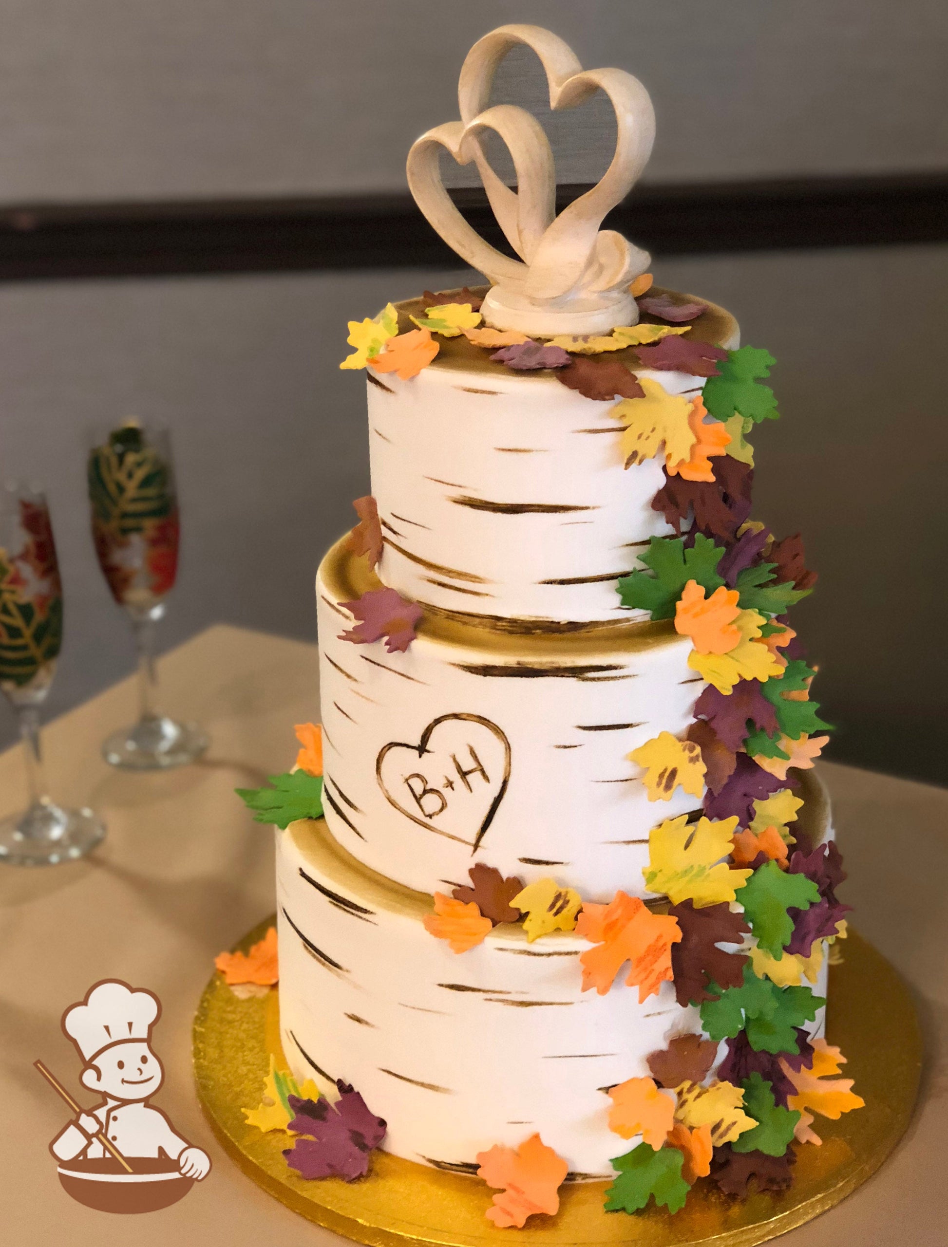 3-tier cake with smooth white icing and decorated with a painted wood grain look and a heart with the initials B + H.