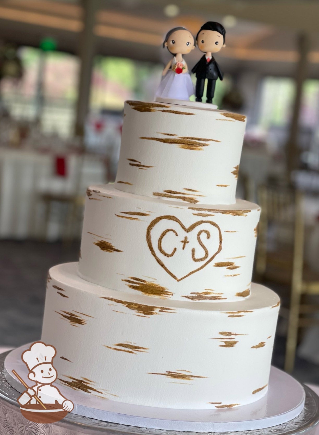 3-tier cake with smooth white icing and decorated with a painted wood grain look and a heart with the initials C + S.