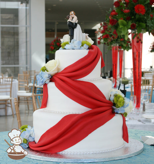 3 tier white fondant cake with red fondant drapes and finised with paster fresh flowers.
