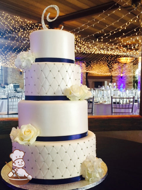4 tier round fondant wedding cake with quilted pattern and silver beads and navy blue satin ribbon wrap on base of each tier.