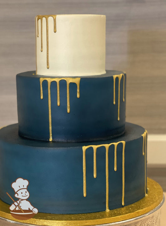 3-tier cake with teal-colored smooth icing on the bottom two tiers and ivory-colored smooth icing on the top tier with metallic gold drip.