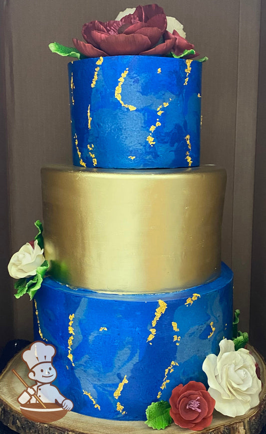 3-tier cake decorated with marble texture on the bottom and top tier in blue colors and gold flake and the middle tier is fully covered in gold.