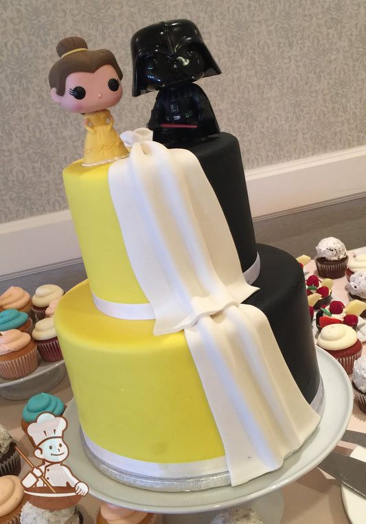 2-tier cake with half in yellow and the other half in black. White fondant drape is laid to divide the colors. Star Wars character topper.