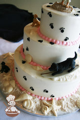 3-tier cake with smooth white icing and decorated with black buttercream dog paws, white chocolate seashells and sugar "sand".
